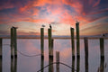 Birds perched on wooden posts in a body of water with a colorful sunset sky. Print by Lisa Lake Photography.